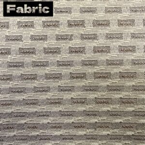 Beige fabric with a subtle brown woven pattern. The texture is slightly raised and has a geometric design.